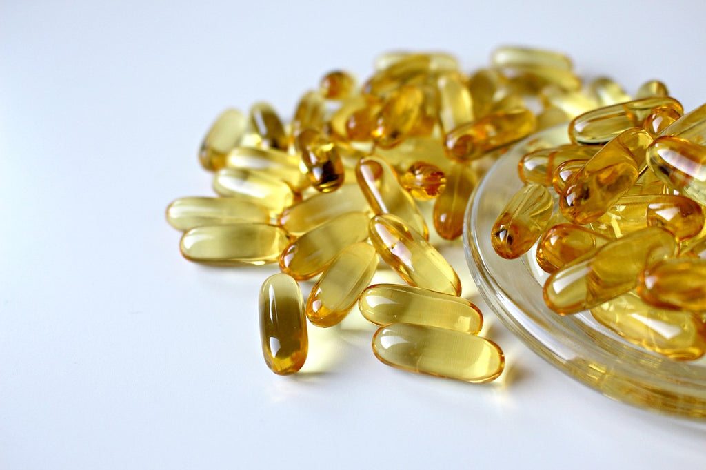 yellow capsules of fish oil on white background